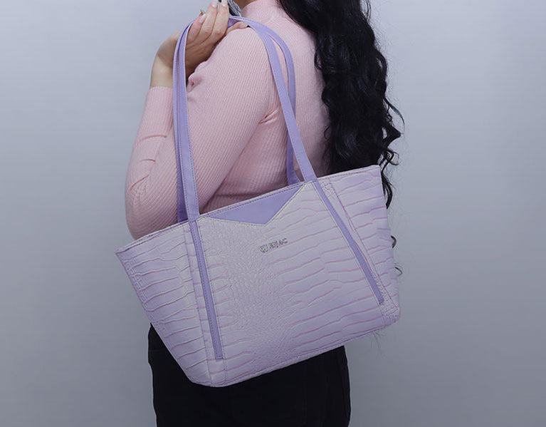 A woman is holding a purple tote bag.