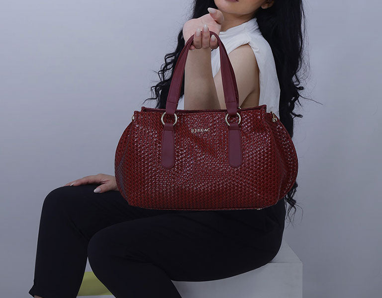 A woman is holding a burgundy handbag.